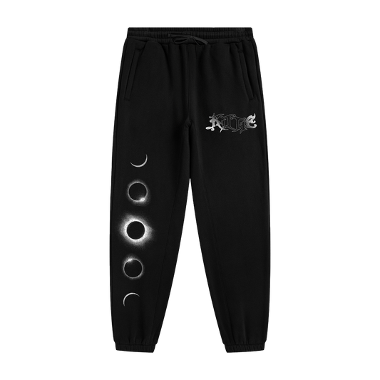 Kittie’s Hecate Black Sweatpants feature a relaxed fit, drawstring waist, white gothic logo on one leg, vertical moon phases on the other, and are crafted from cozy recycled polyester fleece.